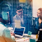 Digital Transformation: Strategy, Challenges, and the Chief Digital Officer's Mandate 4 close-up view focusing on a person's hands typing on the keyboard of a laptop. The laptop screen is visible and displays multiple lines of text that appear to be HTML computer code, set against a dark background theme. The lighting suggests an indoor setting, possibly an office or workspace